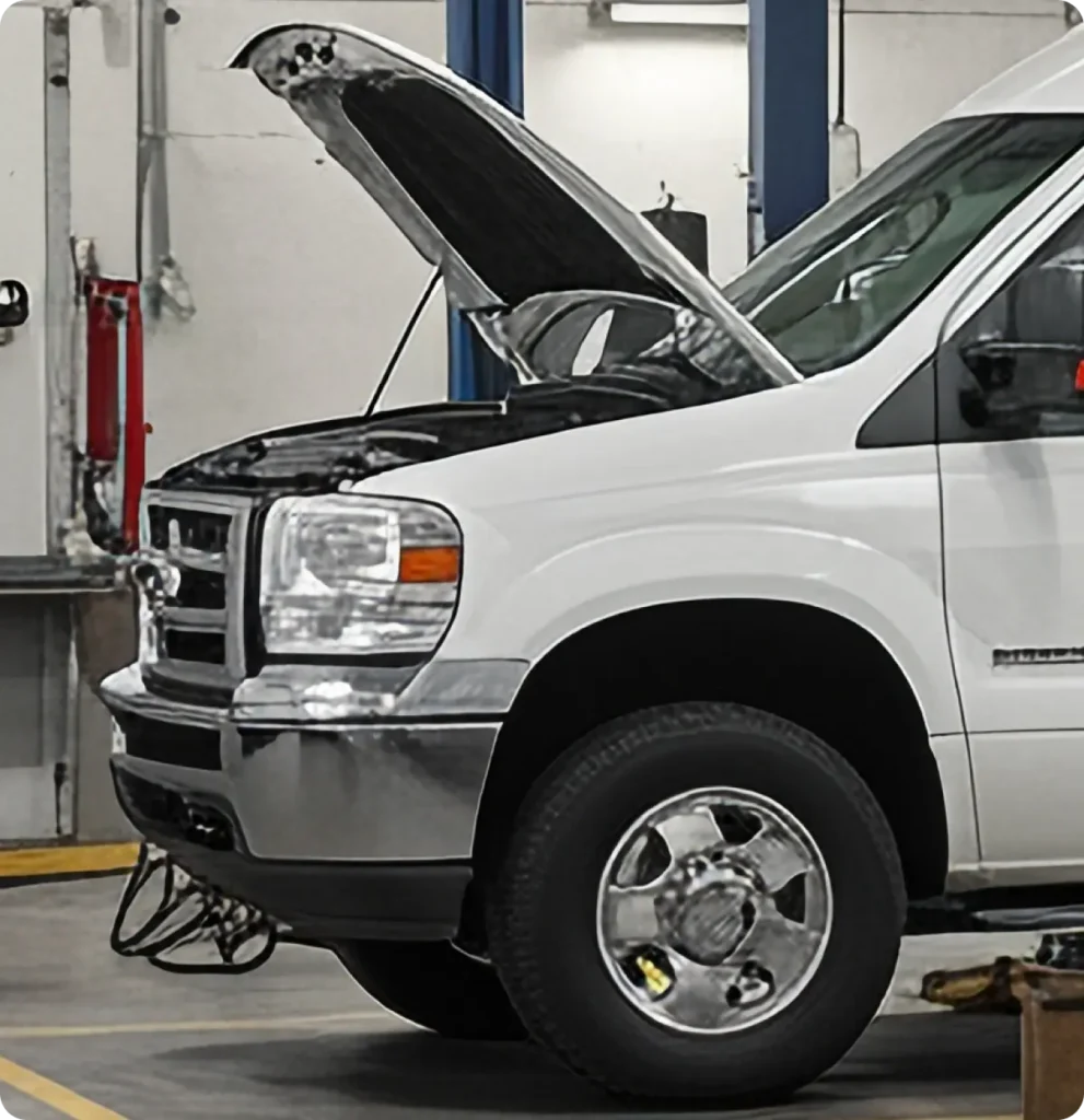 Fleet service, auto repair in Springfield, OR, at Absolute Air & Auto Repair. A white van with its hood open is parked inside an auto repair shop, exposing the engine for maintenance or inspection. The workshop has tools and equipment visible in the background.
