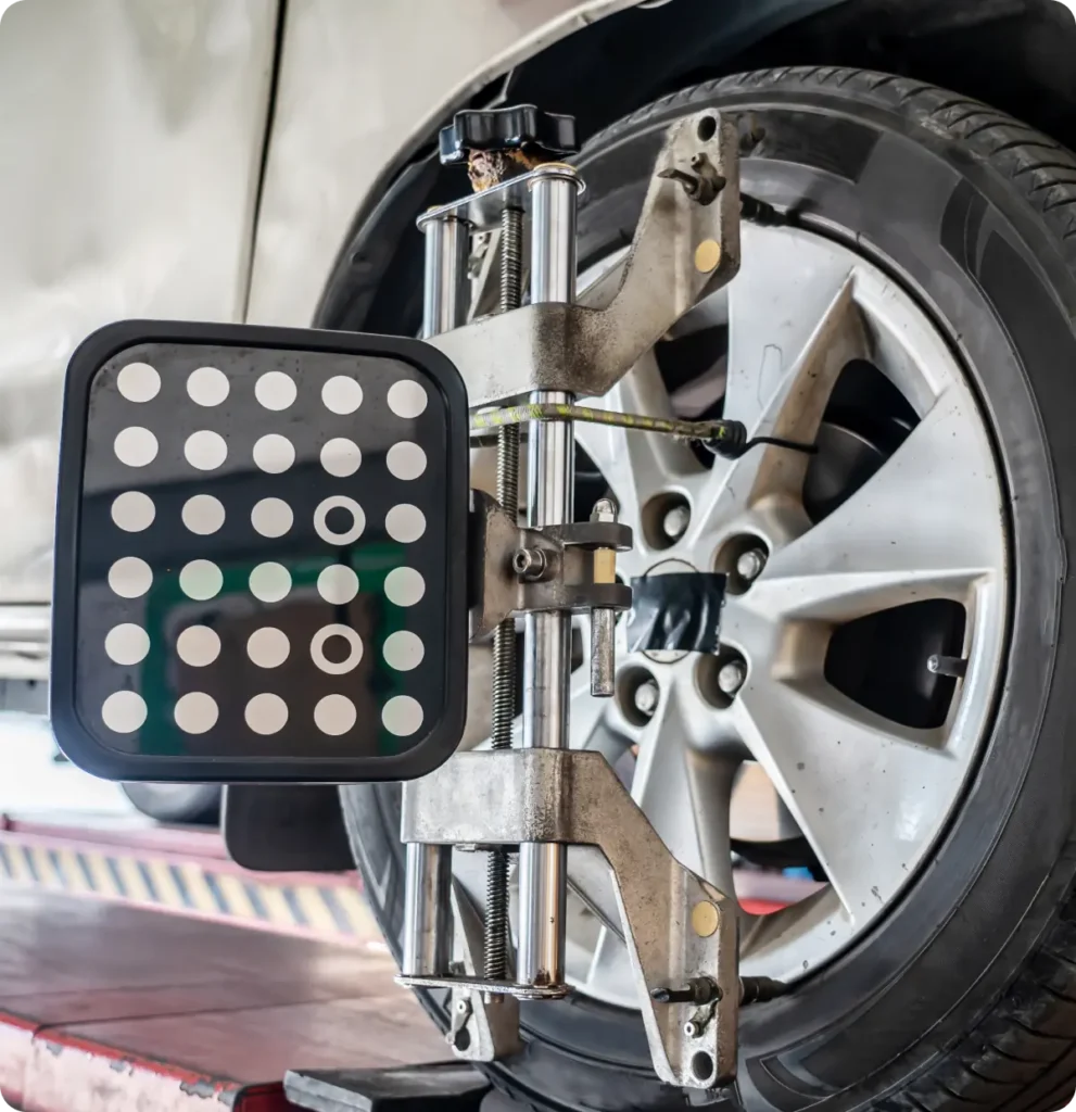 Wheel alignment, auto repair in Springfield, OR, at Absolute Air & Auto Repair. A close-up of a car wheel with a wheel alignment tool and calibration panel attached, indicating the vehicle is being serviced for wheel alignment at an auto repair shop.