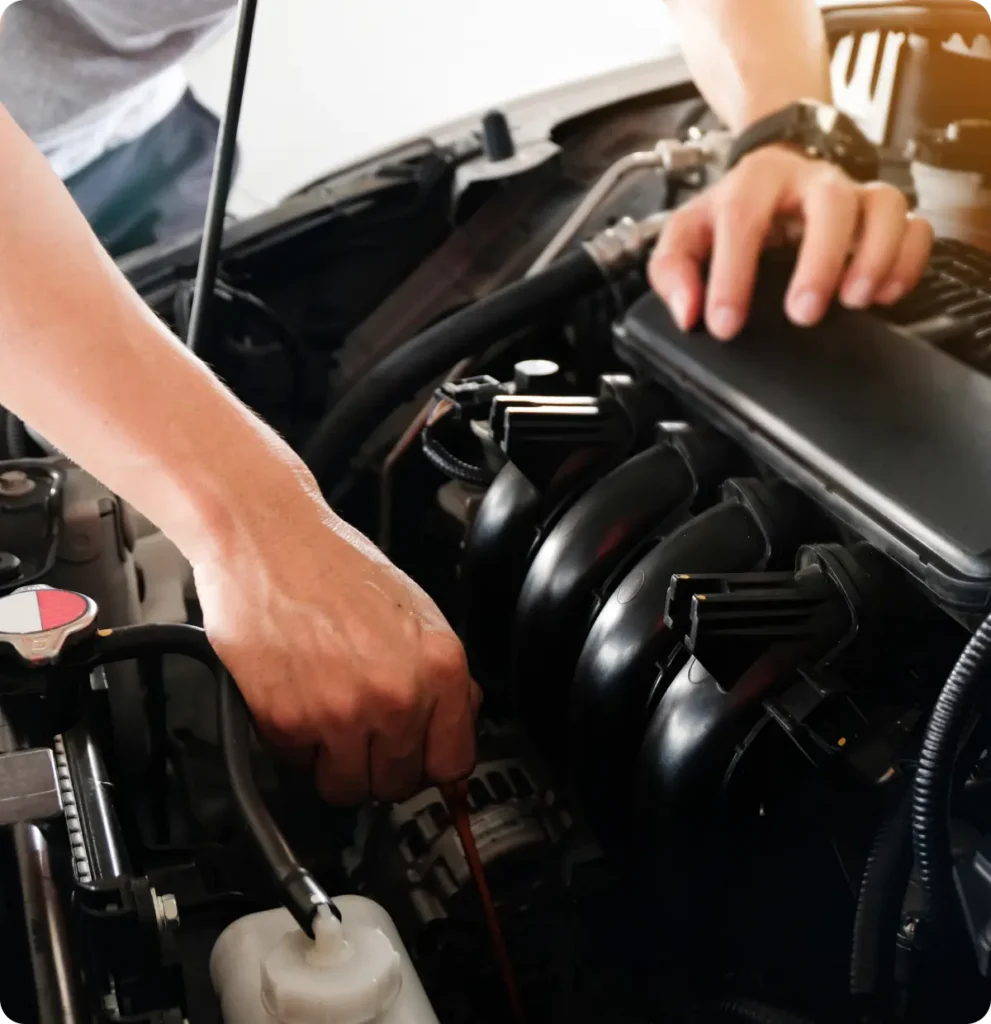 Vehicle inspection, auto repair in Springfield, OR, at Absolute Air & Auto Repair. A person checks a car engine, holding a dipstick and touching engine components under the hood, illustrating car maintenance or repair.