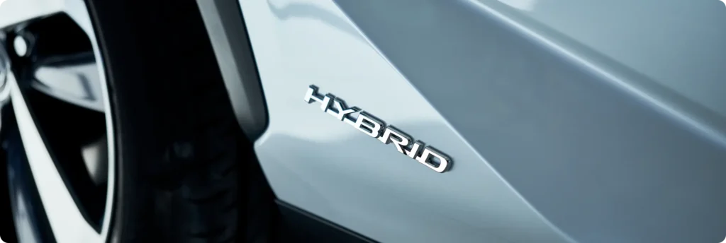 Hybrid auto repair in Springfield, OR, at Absolute Air & Auto Repair. Close-up of a silver car with the word HYBRID in chrome letters on the side, next to a black tire.