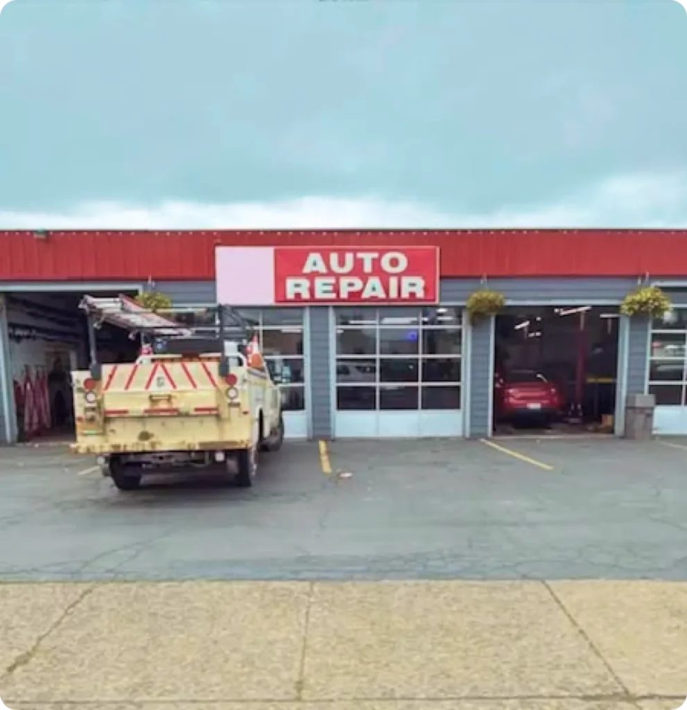 Auto repair in Springfield, OR, at Absolute Air & Auto Repair. A truck is parked outside an auto repair shop with a red and white AUTO REPAIR sign above the entrance. The shop has three open garage bays, with a red car visible inside one bay.