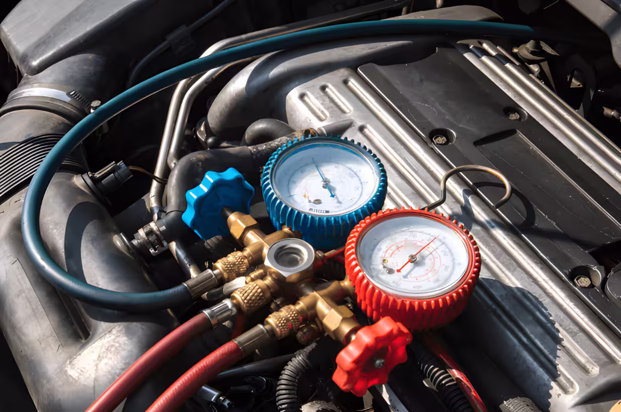 Auto a/c repair in Springfield, OR, at Absolute Air & Auto Repair. Image of an automotive A/C manifold gauges connected to a vehicle engine during professional air conditioning system diagnostics, testing refrigerant pressure for accurate auto A/C repair.