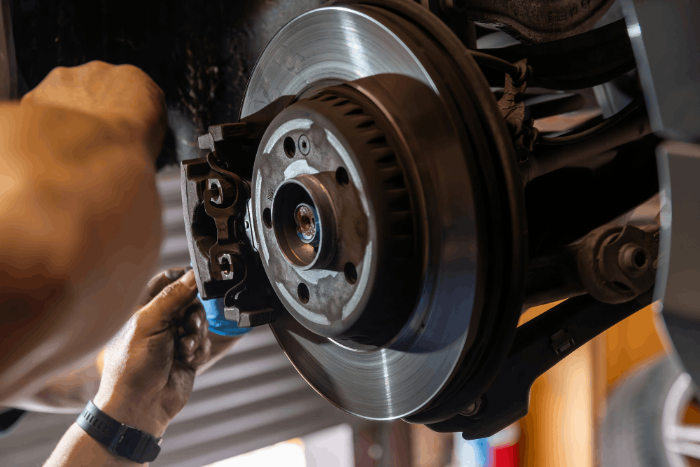 Car maintenance, auto repair in Springfield, OR at Absolute Air & Auto Repair. Image of a technician inspecting a vehicle’s brake rotor and caliper during professional brake service.